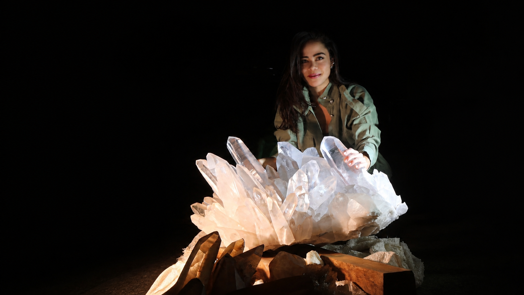 Bruna de Paula presenting a monumental clear quartz cluster against a black background