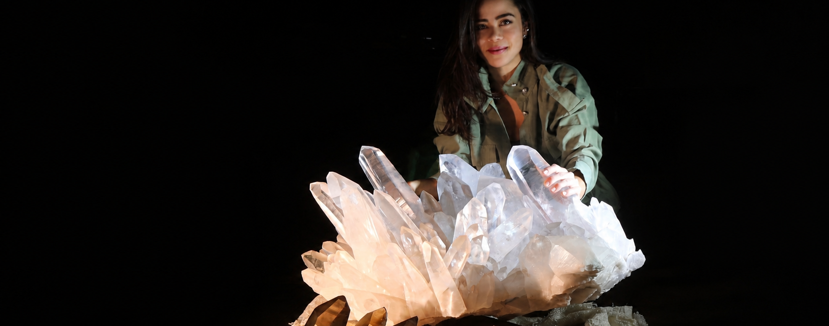 Bruna de Paula presenting a monumental clear quartz cluster against a black background