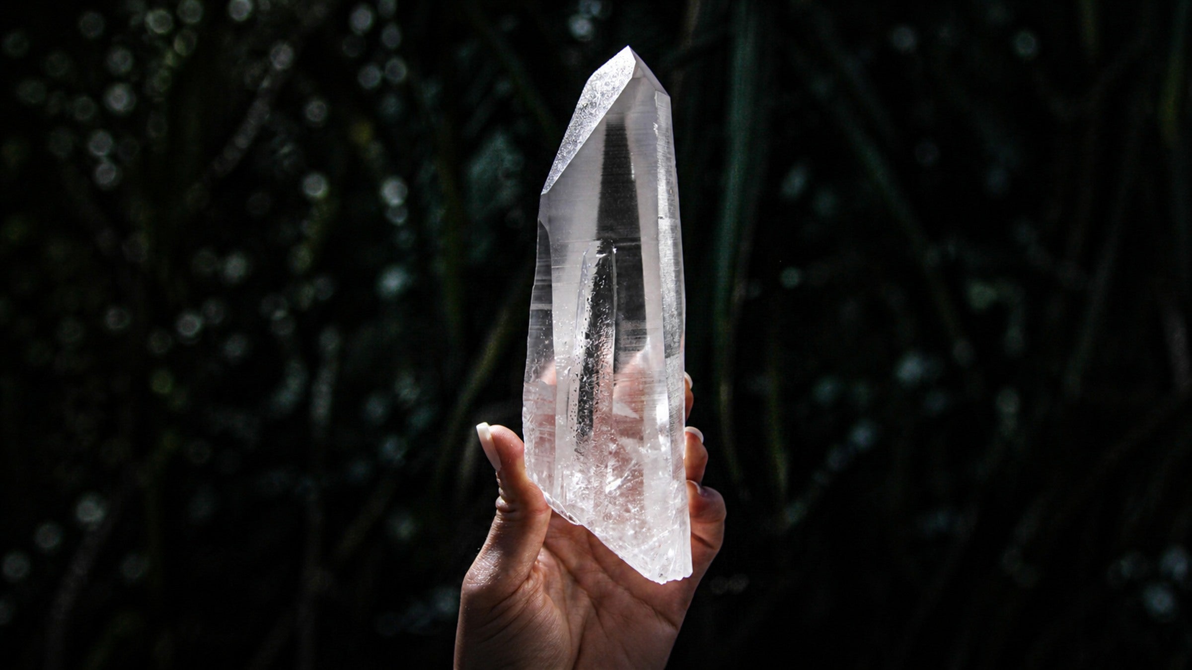 Natural Lemurian Seed quartz point with horizontal striations against a dark background