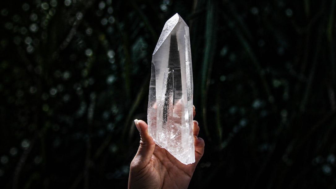 Natural Lemurian Seed quartz point with horizontal striations against a dark background