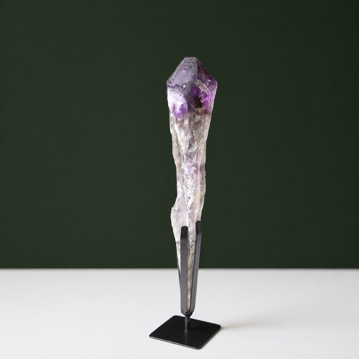 Naturally terminated amethyst wand with growth markings on black metal stand