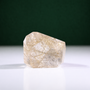 Polished rutilated quartz freeform, 223 g, main view on a white surface with a dark green background.