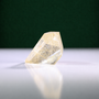 Polished rutilated quartz freeform, 79 g, main view on a white surface with a dark green background.