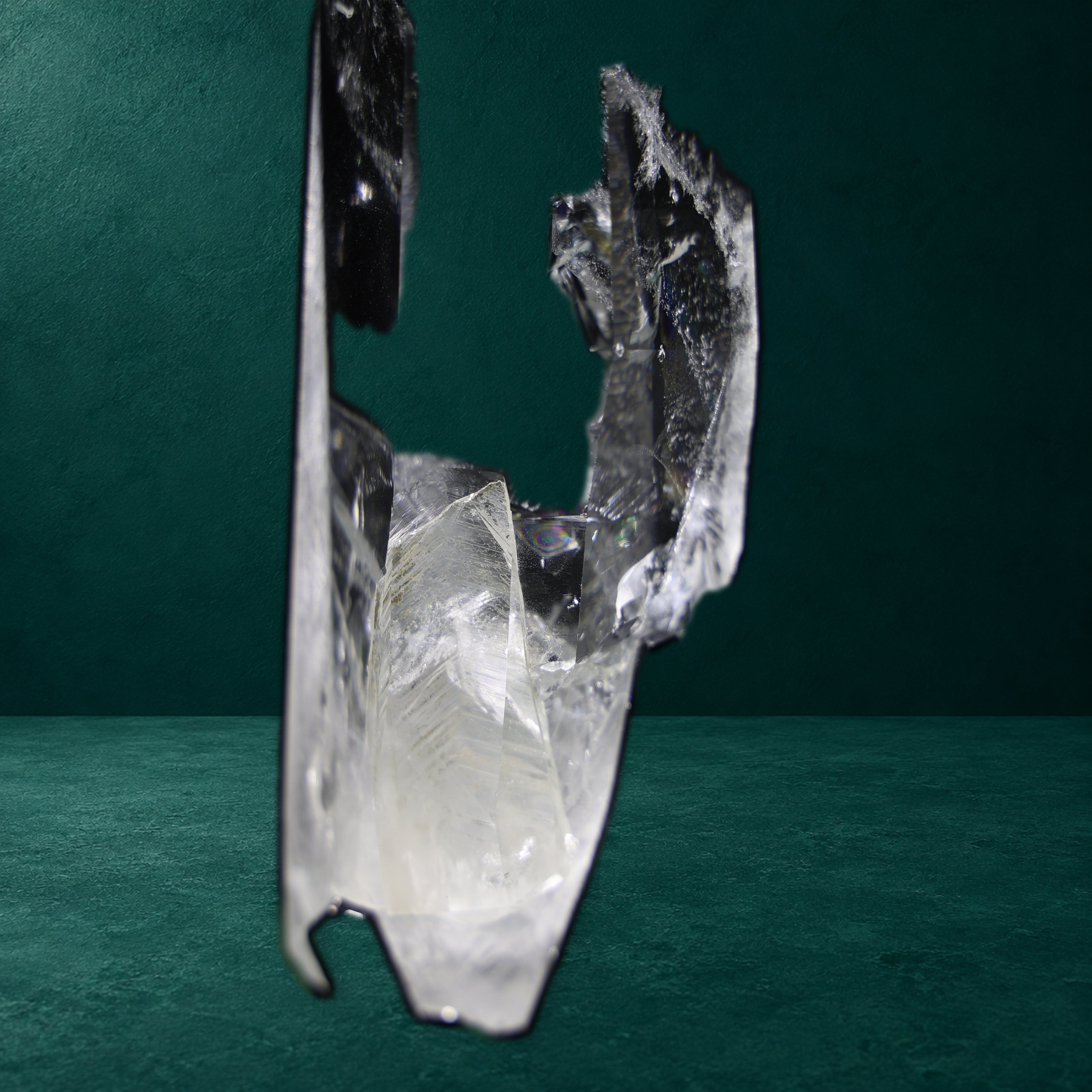 Close view of the self-healed lower formation of a tall Clear Lemurian quartz point against an Ita green background.