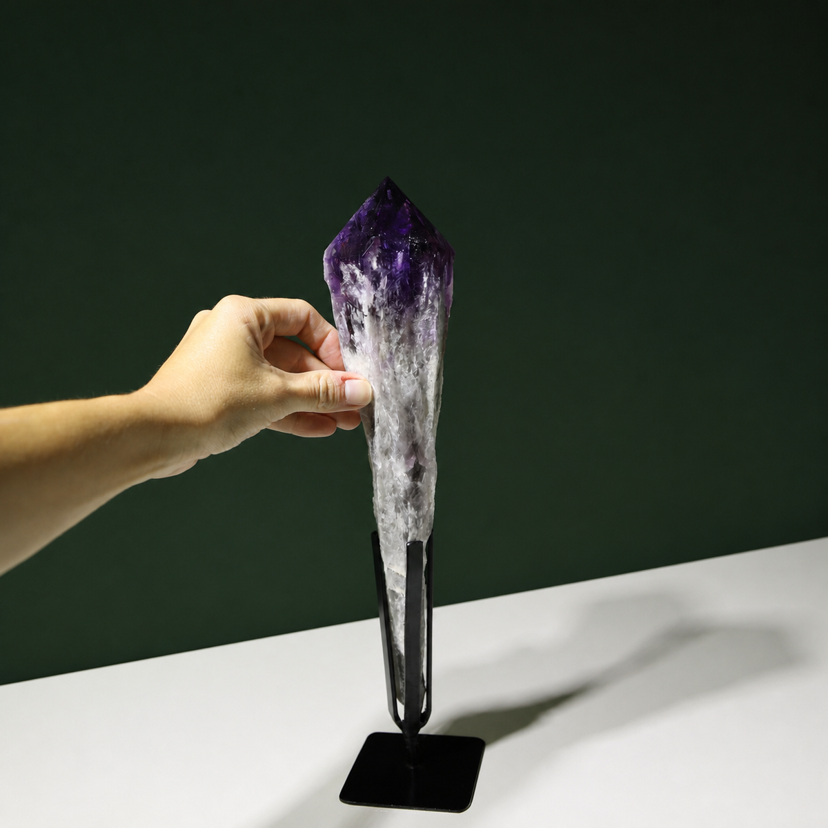 Deep violet amethyst wand shown with hand for scale
